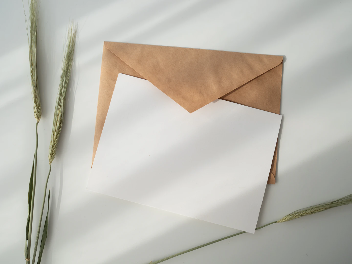 Enveloppe kraft et feuille blanche posées sur une surface claire.